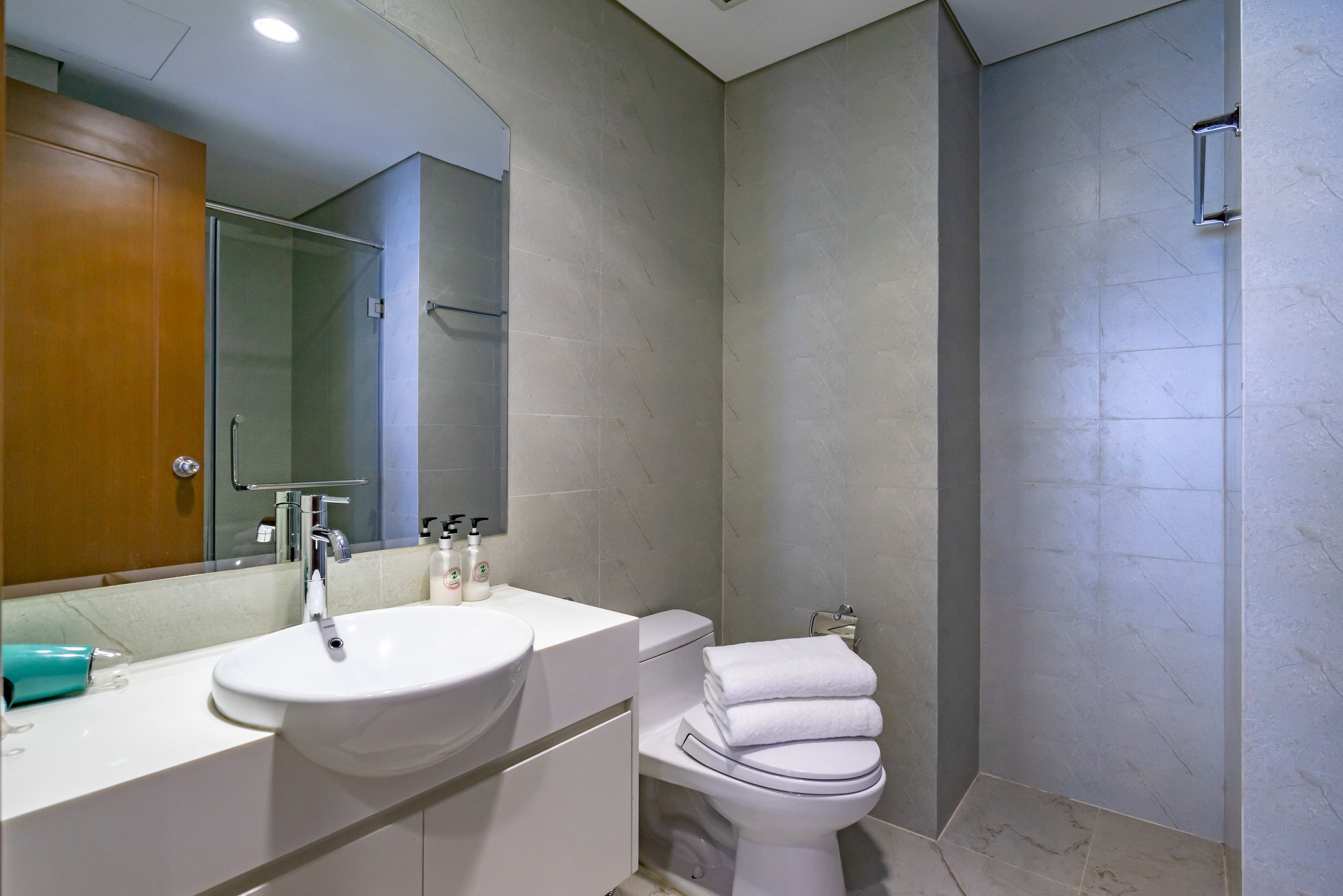 A modern bathroom with a white sink, mirror, and toilet.