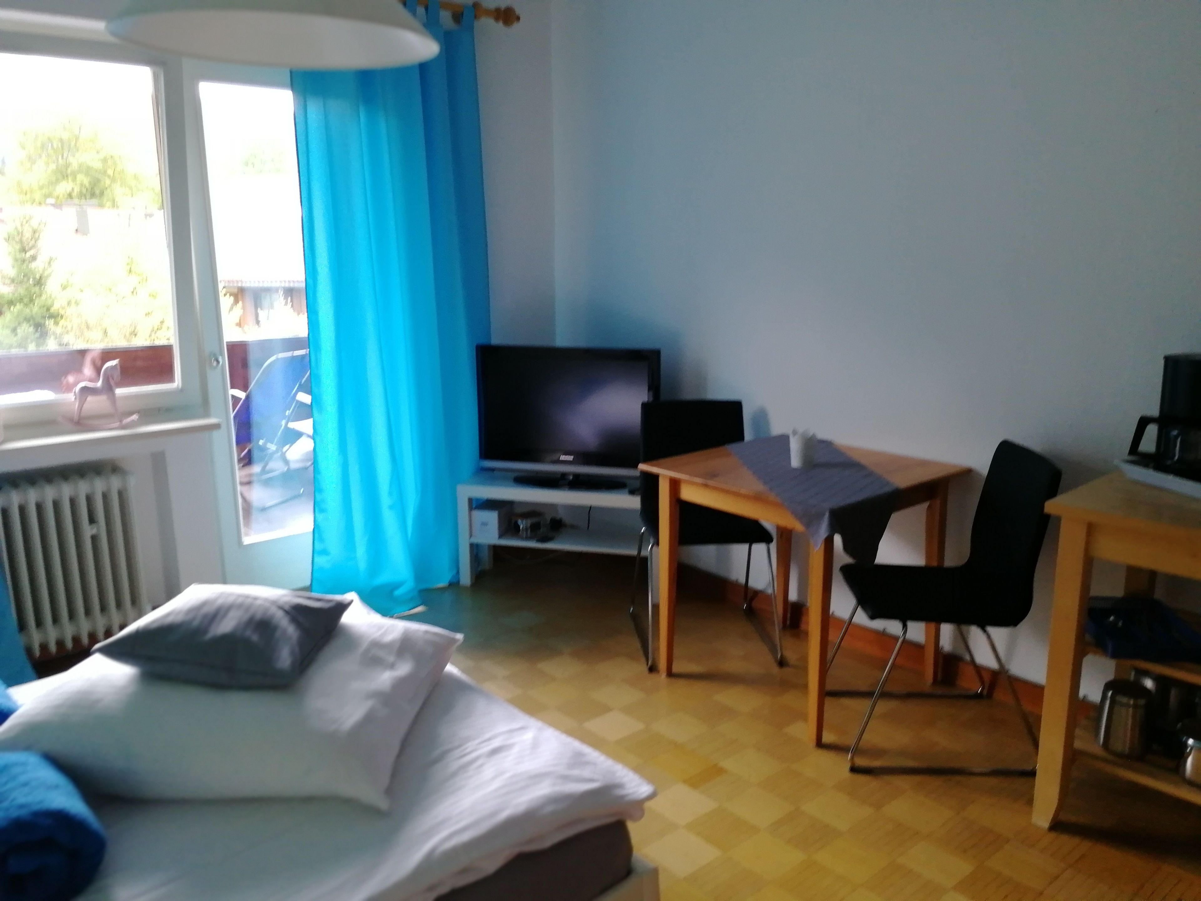 Quarto de hotel com cama, televisão, mesa e cadeira.