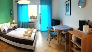 Un dormitorio con cama, escritorio, silla, armario y ventana con cortinas.