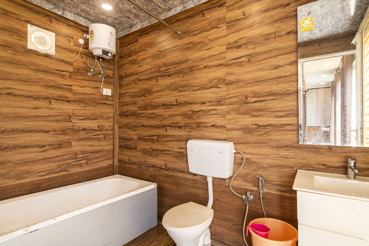 Un baño con pared de madera, una bañera, un inodoro, un lavabo y un espejo.