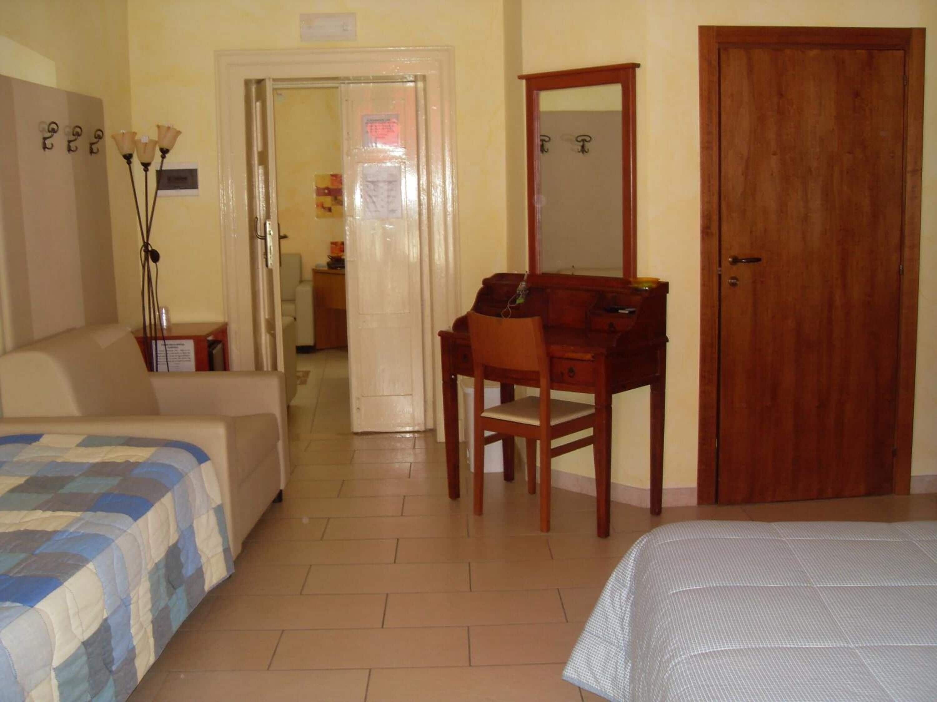 Une chambre à coucher comprenant un lit, un bureau, une chaise, une armoire et une porte.