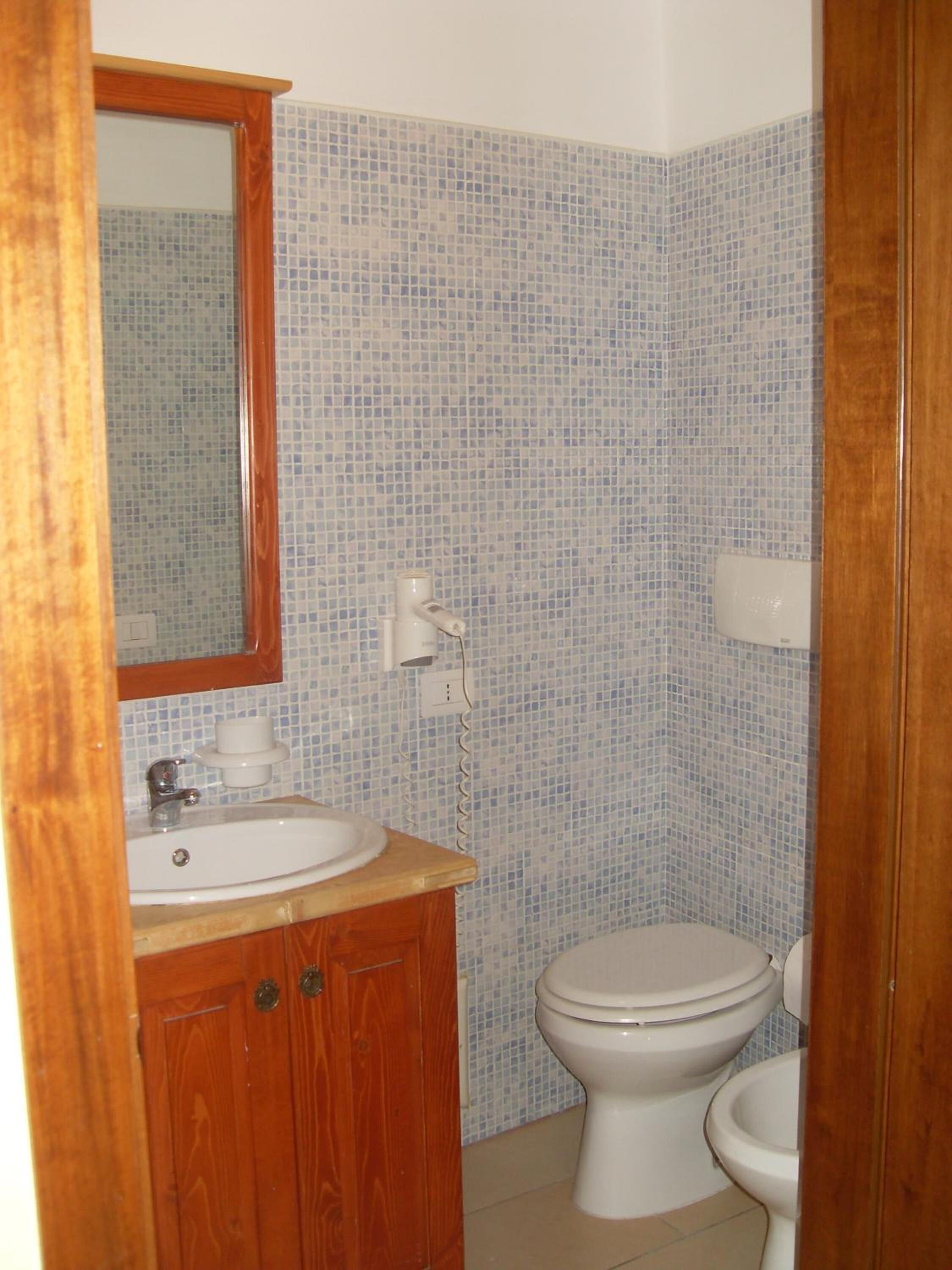 Ein Badezimmer mit einem Holzwaschtisch, einem weißen Waschbecken, einem Spiegel und einer Toilette.