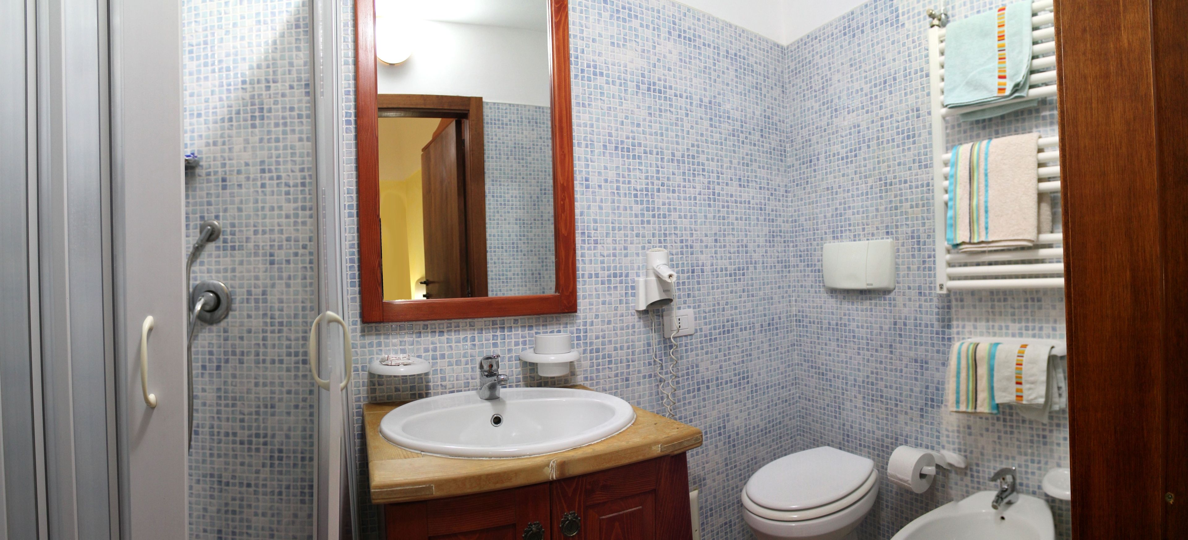 A bathroom with a sink, mirror, toilet, and towel rack.