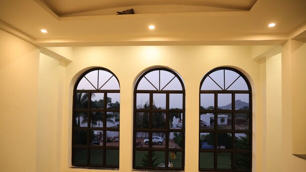 A room with three large arched windows, a marble floor, and a ceiling with recessed lighting. - Winter Mountain Resort (Pushkar)