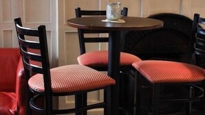 A dining area with a round table, four chairs, and a vase on the table.