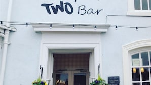 The exterior of Chapter Two Bar, featuring a white facade with a black sign above the entrance.