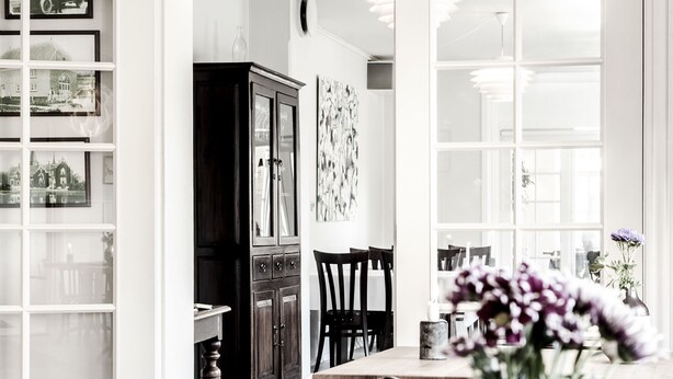 Une cuisine moderne avec un coin repas, comprenant un meuble en bois, un plan de travail en marbre et un vase rempli de fleurs.