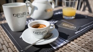 A table with a teapot, a cup of coffee, and a glass of orange juice on a placemat. - Opera Home Principe Umberto (Naples)