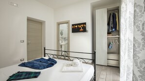 A bedroom with a bed, a wardrobe, a mirror, and a television. - Opera Home Principe Umberto (Naples)