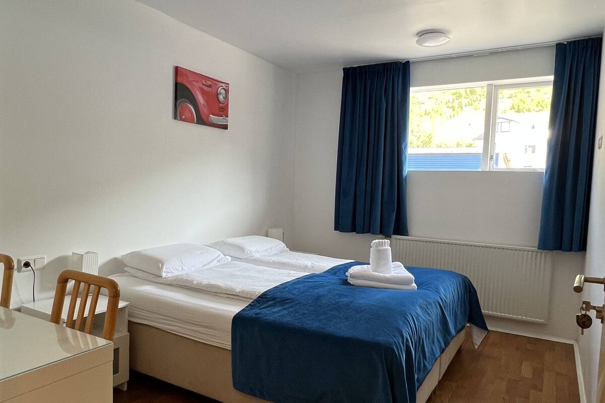 Une chambre avec un lit, un bureau et une fenêtre avec des rideaux.