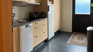 Une cuisine avec des meubles de rangement en bois, un lave-vaisselle, une cuisinière et un réfrigérateur.