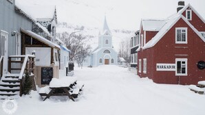 Une rue enneigée avec une église et un bâtiment portant l’inscription « Markadur ».