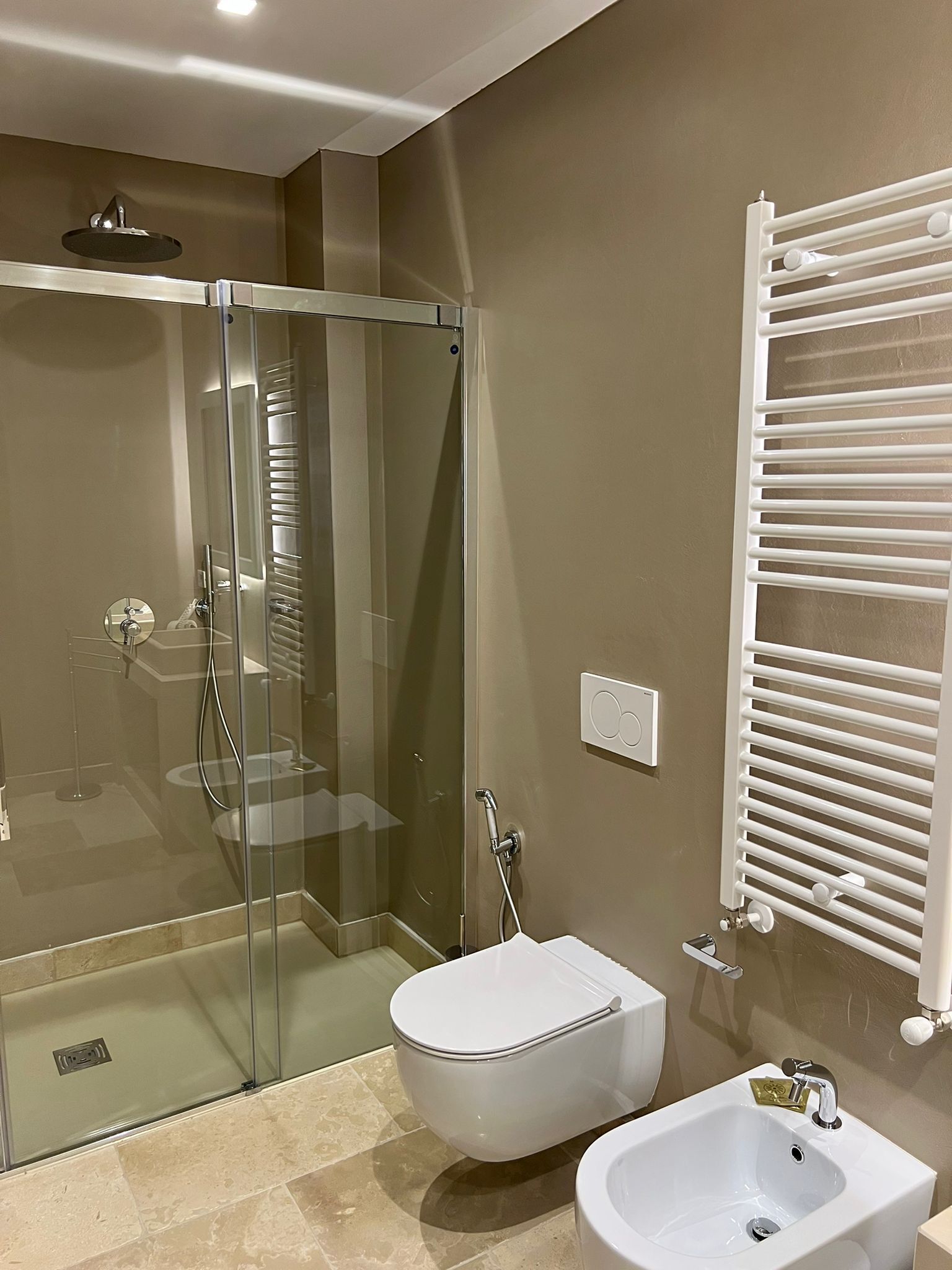 A modern bathroom with a glass-enclosed shower, a white bidet, and a white sink.