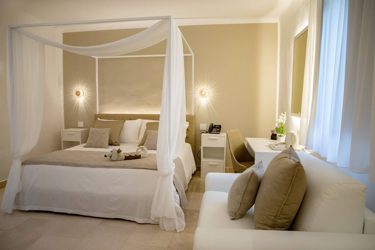 A bedroom with a four-poster bed, bedside tables, a desk, and a chair.