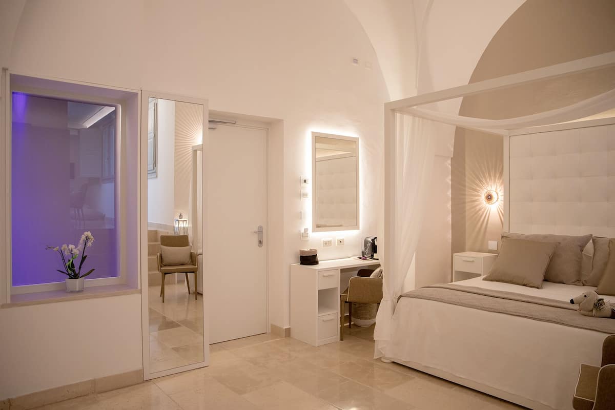 A modern bedroom with a bed, bedside table, and a desk with a chair.