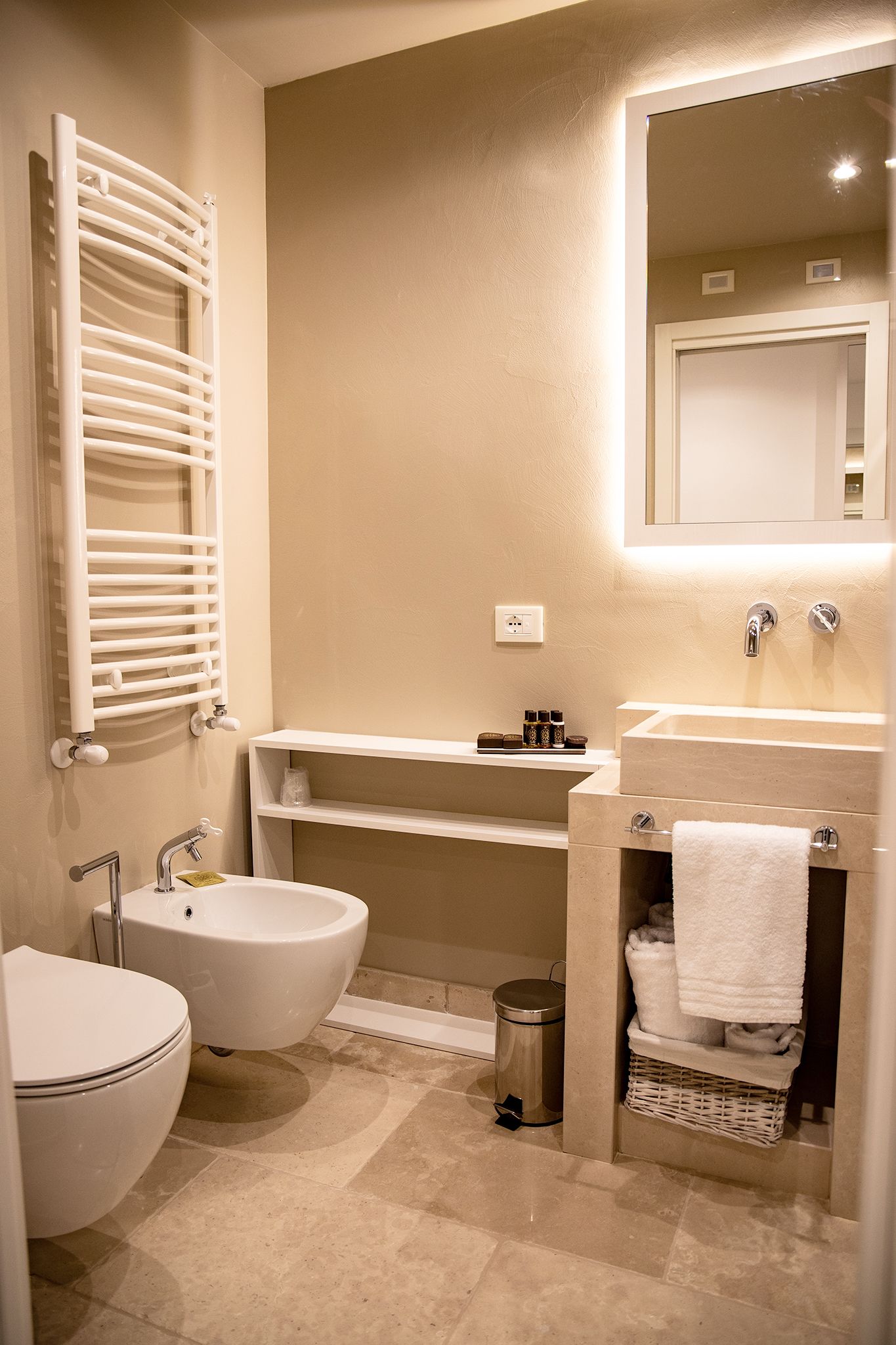 A bathroom with a toilet, bidet, sink, and towel rack.