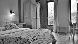 Een slaapkamer met een bed, nachtkastje, garderobe, bureau en stoel.
