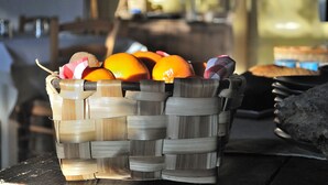 Een gevlochten mand vol sinaasappels op een houten tafel.