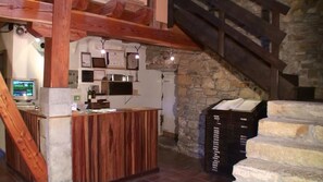 Un intérieur rustique avec un comptoir d’accueil en bois, des murs en pierre et un escalier.