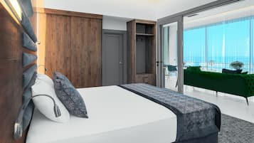 Une chambre d’hôtel moderne avec un grand lit, des panneaux de bois, un canapé vert et un balcon avec vue.