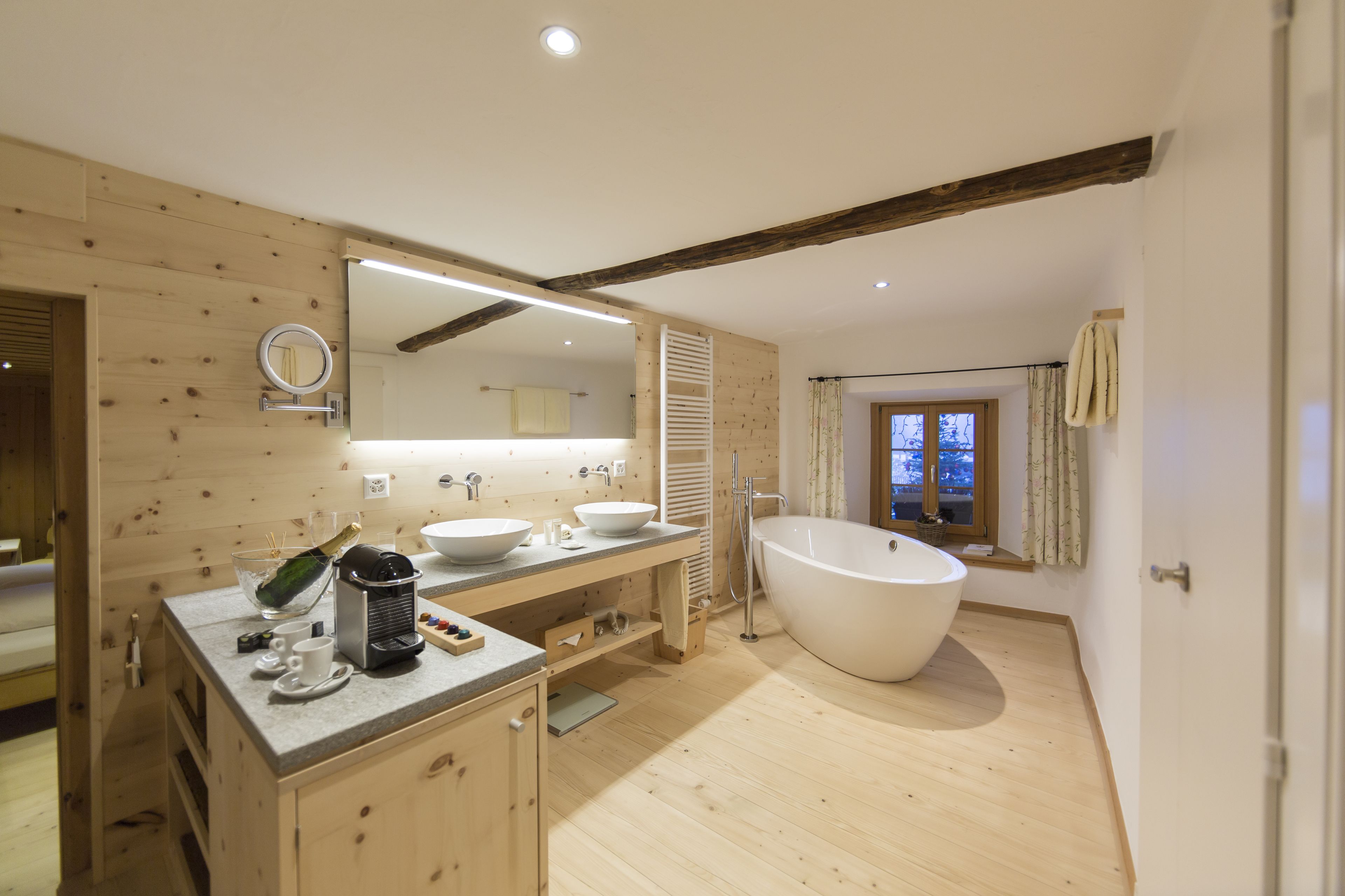 Een moderne badkamer met houten wanden, een ruime badkuip en een wastafel met spiegel.