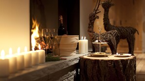 Une table décorée de bougies, d’une bouteille de vin et d’une statuette de cerf.