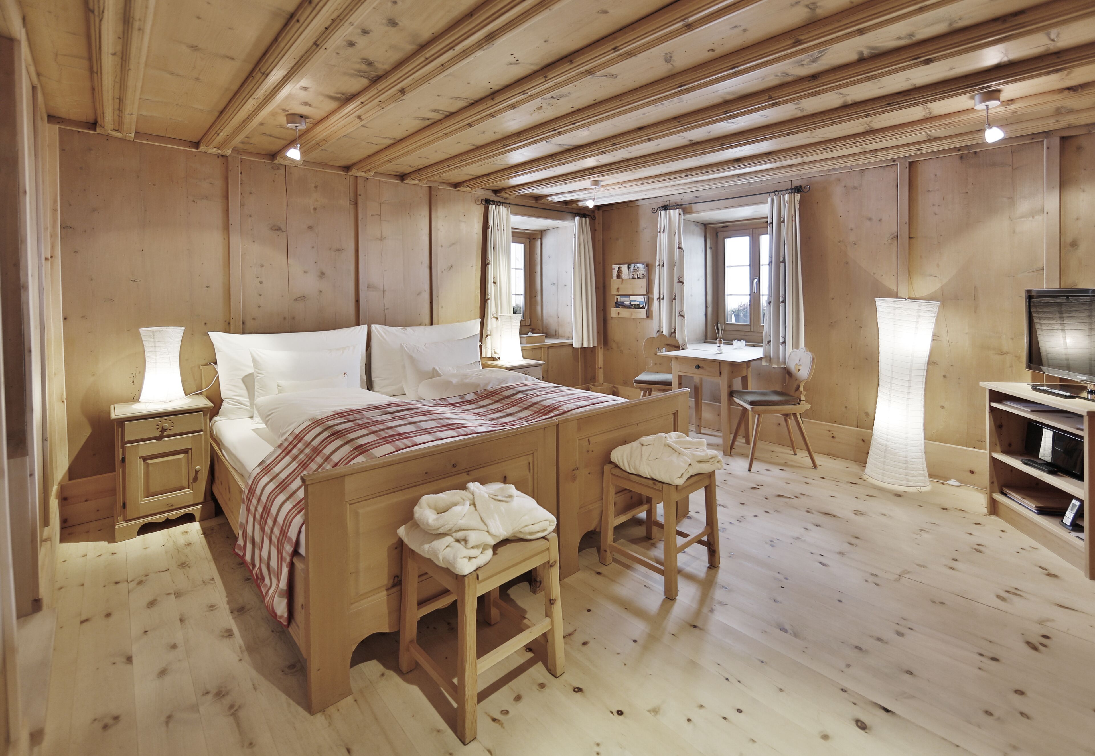 Une pièce en bois avec un lit, des tables de chevet, un bureau et une chaise.