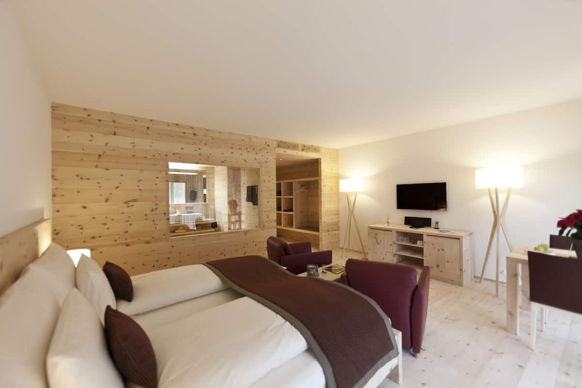 Une chambre d’hôtel dotée d’un grand lit, d’un bureau avec un téléviseur à écran plat, d’une armoire et d’un coin salon comprenant une chaise et une table.