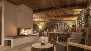 Un salon confortable avec une cheminée, des sièges et un bar où sont exposées des bouteilles.