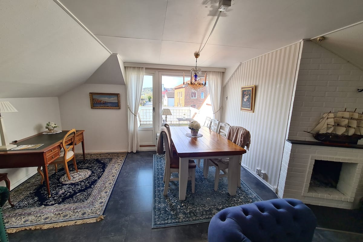 Uma sala de jantar com mesa e cadeiras de madeira, um candelabro e uma lareira.
