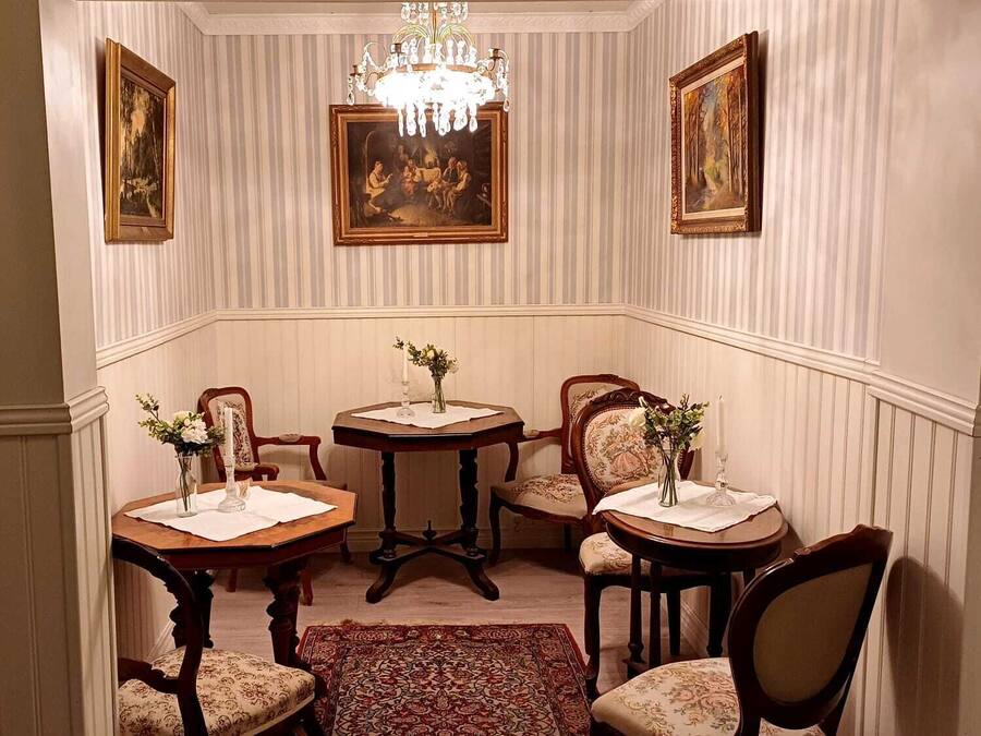 Une salle à manger avec un lustre, quatre tables en bois et des chaises.