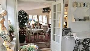Un comedor con una araña, una planta grande en maceta y un cuenco de flores.