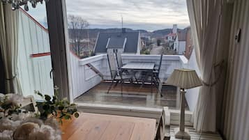 A balcony with a wooden table and chairs, a lamp, and a view of a residential area.
