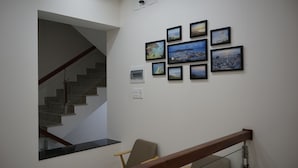 A staircase with a wooden handrail leading to a landing where a chair is placed. - Khach San Sao Viet (Quy Nhon)