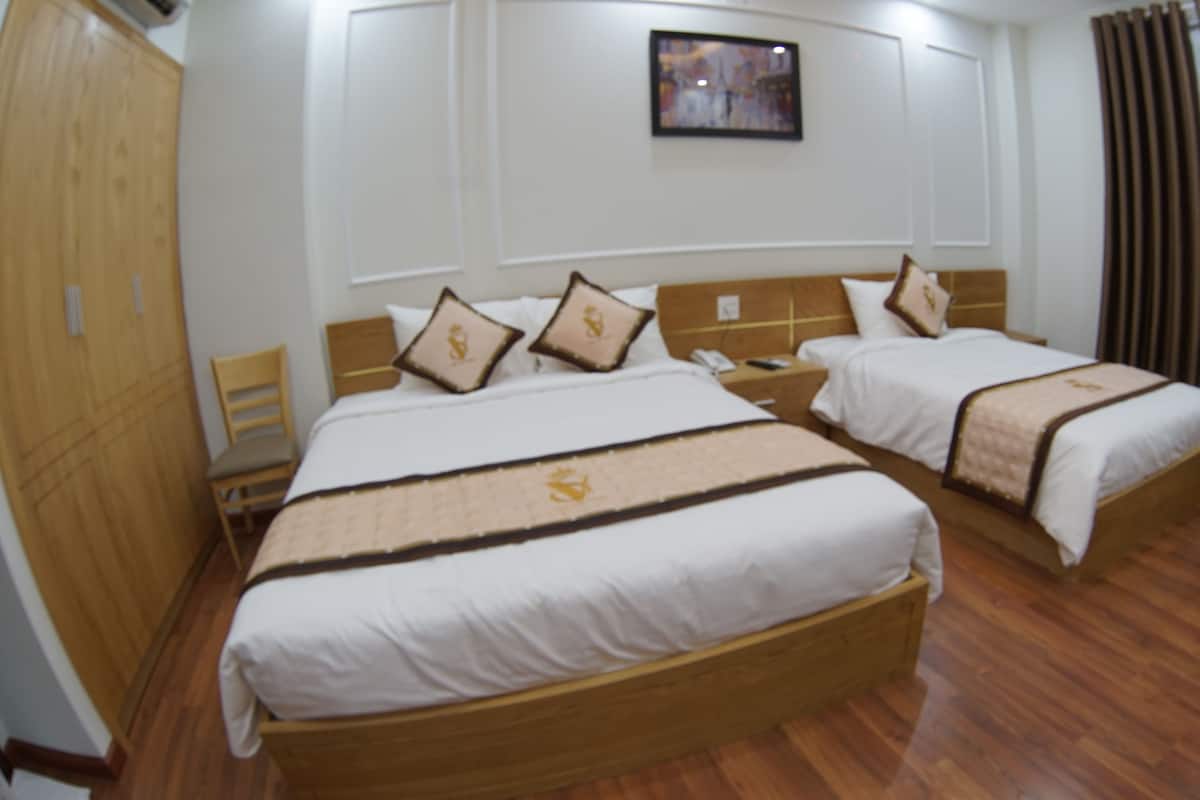Une chambre d’hôtel avec deux lits, des têtes de lit en bois et un tableau encadré au mur.
