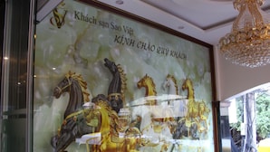 A framed artwork of horses in motion, with text in Vietnamese, displayed in a hotel setting. - Khach San Sao Viet (Quy Nhon)