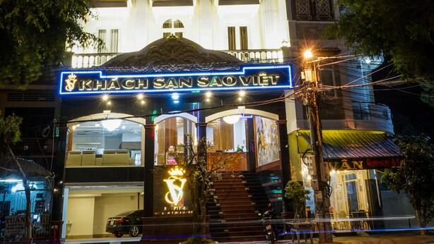 A multi-story hotel with illuminated signage, balconies, and a prominent entrance. - Khach San Sao Viet (Quy Nhon)