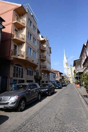 Una calle empedrada flanqueada por edificios de varios pisos, algunos con balcones.