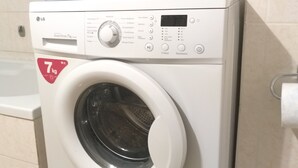 A front-loading washing machine with a digital display and control panel, located in a bathroom with a bathtub and toiletries. - Comfortable apartment for your holidays, in the center of Athens. (Kallithea)