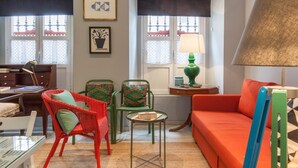 A living room with a red sofa, green and red wicker chairs, a small table with a lamp, and a desk with a lamp. - BEAUTIFUL APT DESIGN 1 BED SEVILLA CENTRO-FULL_AC (Sevilla)