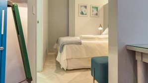 A bedroom with a bed, a nightstand, a lamp, and a blue chair. - BEAUTIFUL APT DESIGN 1 BED SEVILLA CENTRO-FULL_AC (Sevilla)