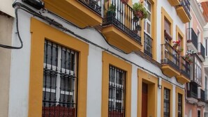 A row of yellow and white buildings with balconies, featuring wrought iron railings and potted plants. - BEAUTIFUL APT DESIGN 1 BED SEVILLA CENTRO-FULL_AC (Sevilla)