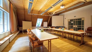 Una sala de conferencias con una larga mesa, sillas y una pantalla para proyector.