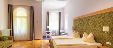 A hotel room with a large bed, a desk, a chair, and a sofa.