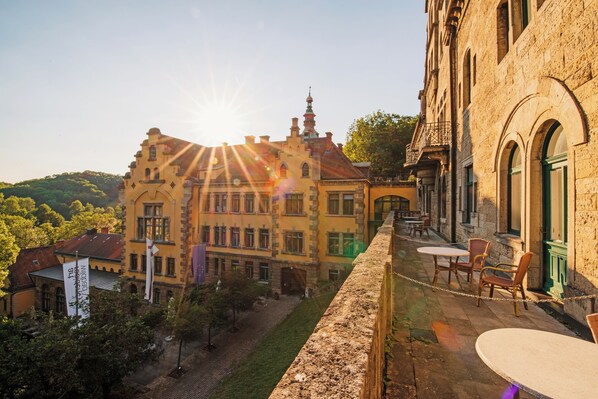 A courtyard with a stone wall, outdoor seating, and a building with a tower.