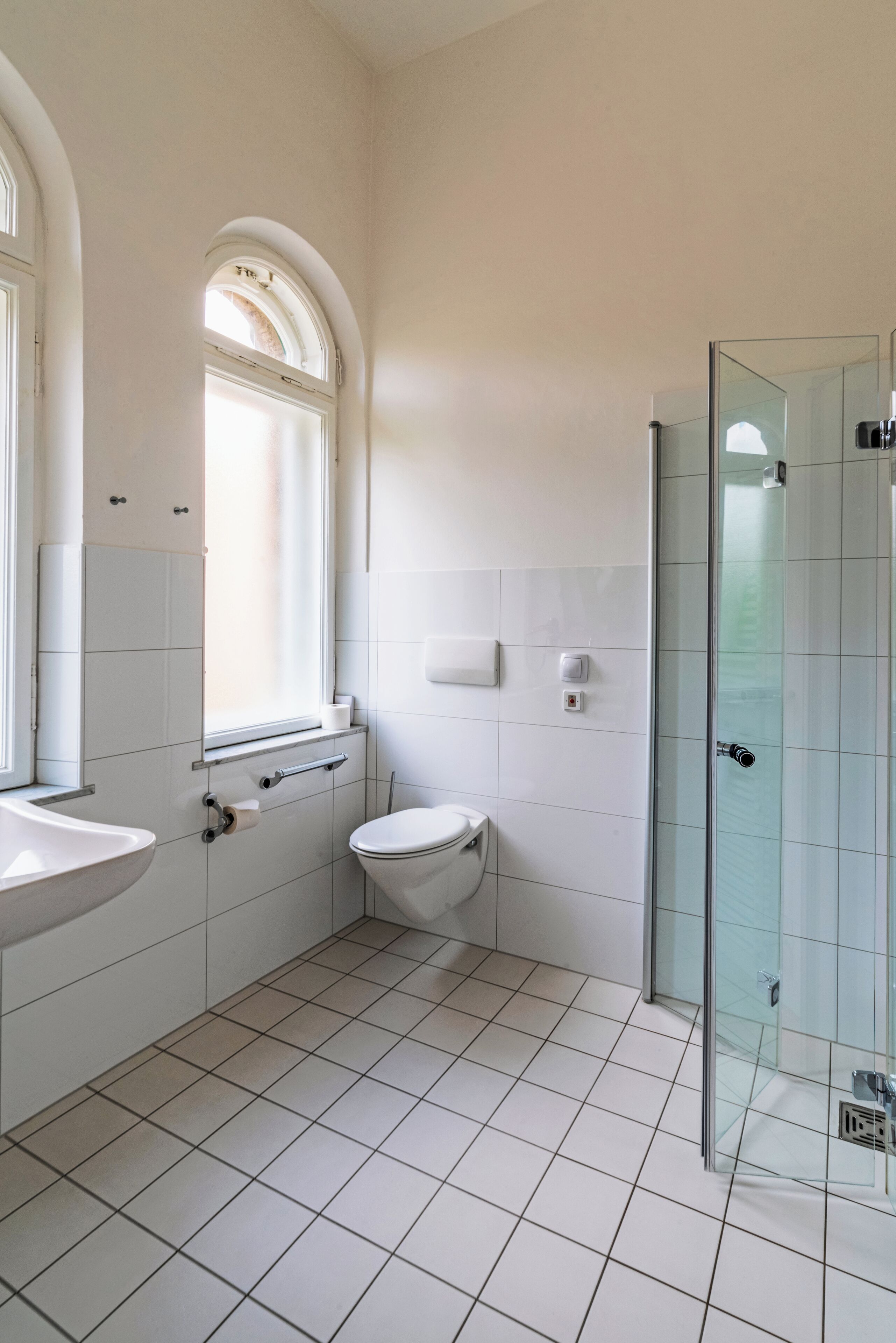 Un baño moderno con inodoro, lavamanos y cabina de ducha con mampara de vidrio.