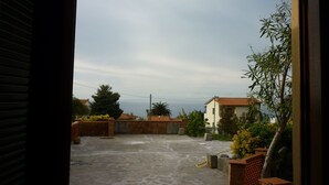 A rooftop patio with a view of the sea, surrounded by vegetation and a building with a tiled roof. - Elba island. Panoramic house at the Zanca, 3 bedrooms, 8 pax. large outdoor area  (Zanca-sant'andrea)