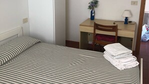 A bedroom with a bed, a desk, a chair, a mirror, and a small plant. - Elba island. Panoramic house at the Zanca, 3 bedrooms, 8 pax. large outdoor area  (Zanca-sant'andrea)