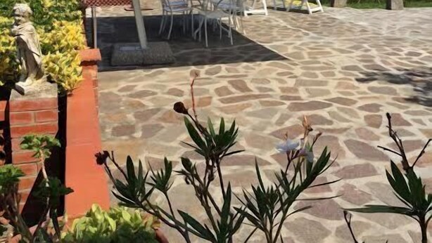 An outdoor patio with a stone floor, white chairs, and a large umbrella. - Elba island. Panoramic house at the Zanca, 3 bedrooms, 8 pax. large outdoor area  (Zanca-sant'andrea)