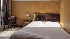 Una habitación de hotel con una cama, una silla, una mesita y una lámpara.